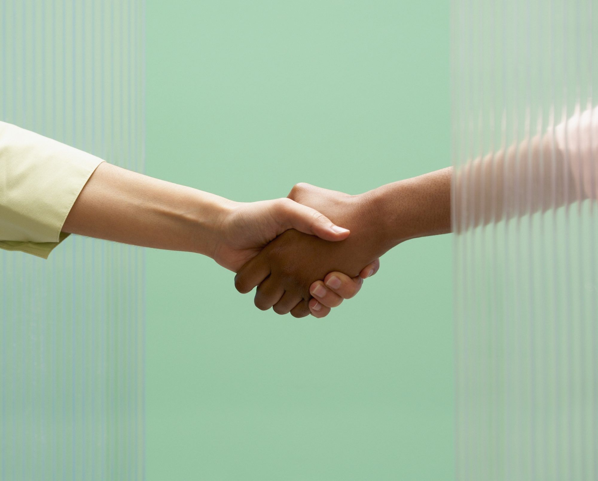 Comment faire le suivi après un entretien d'embauche : deux personnes se serrant la main sur fond vert