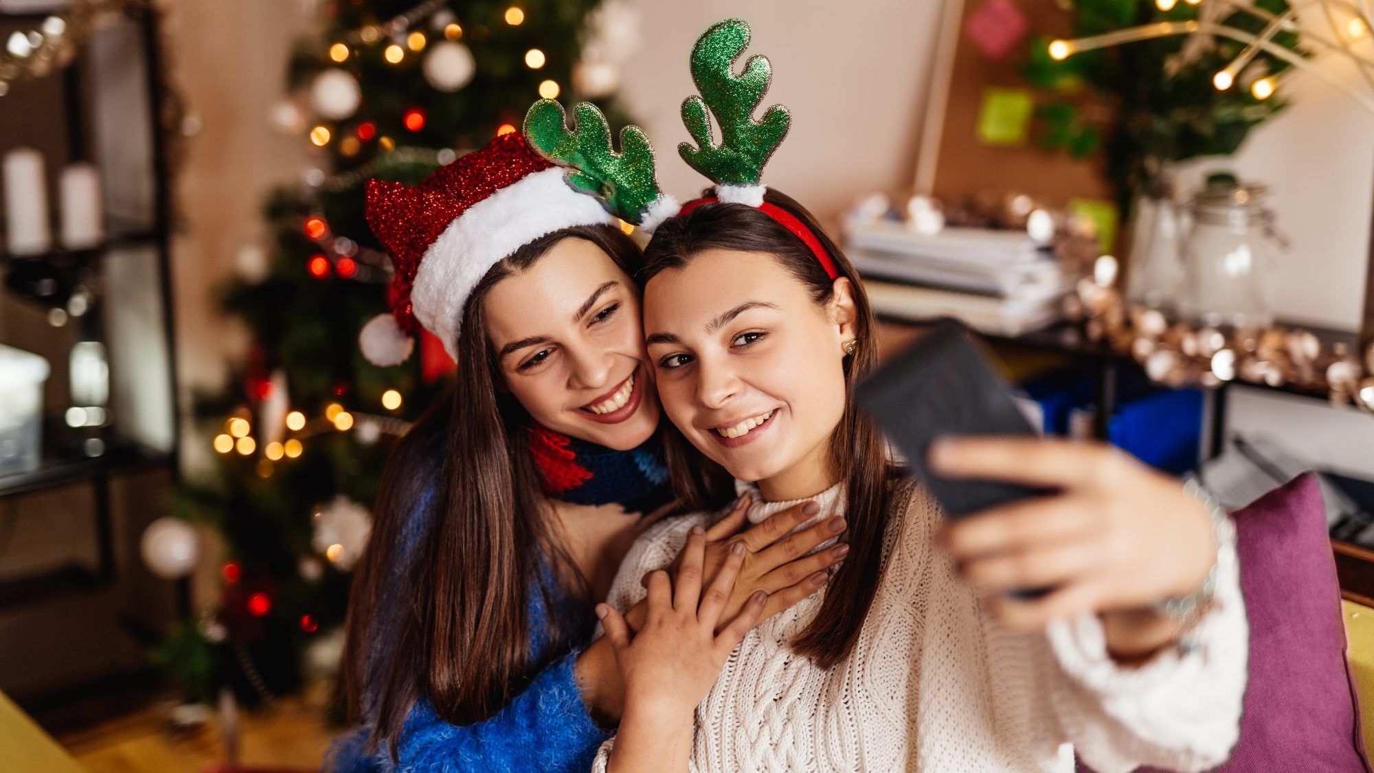 2020'de koronavirüs sırasında Noel nasıl güvenle kutlanır - kız kardeşler Noel şapkalarıyla birlikte fotoğraf çekiyorlar