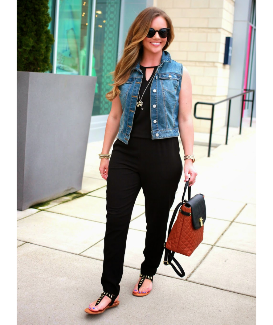 Frau trägt ärmellose Jeansjacke über schwarzem Overall