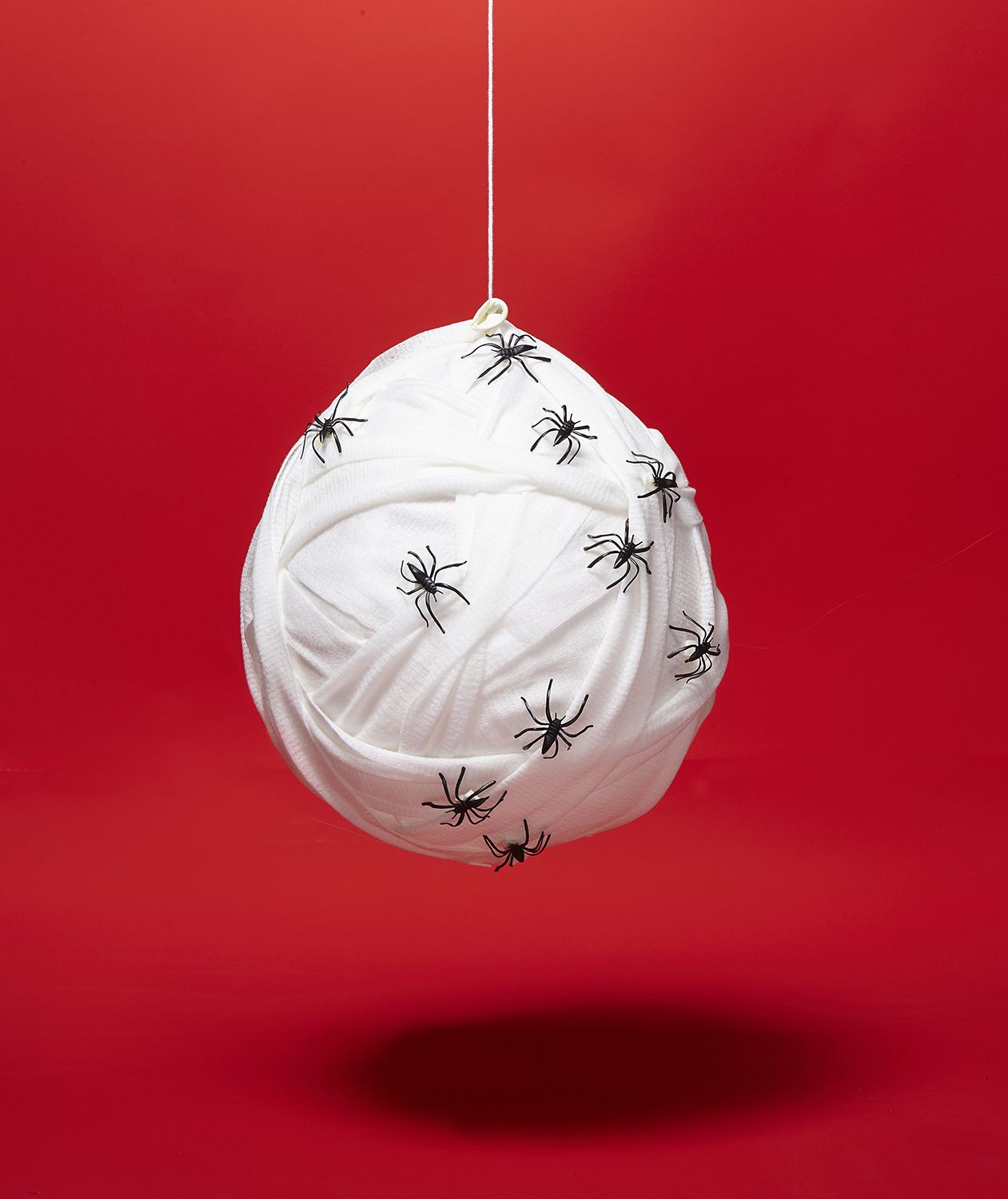 DIY Halloween-sisustusideat: Hämähäkinpesä valmistettu riisillä täytetystä ilmapallosta, joka on kääritty sideharsoon