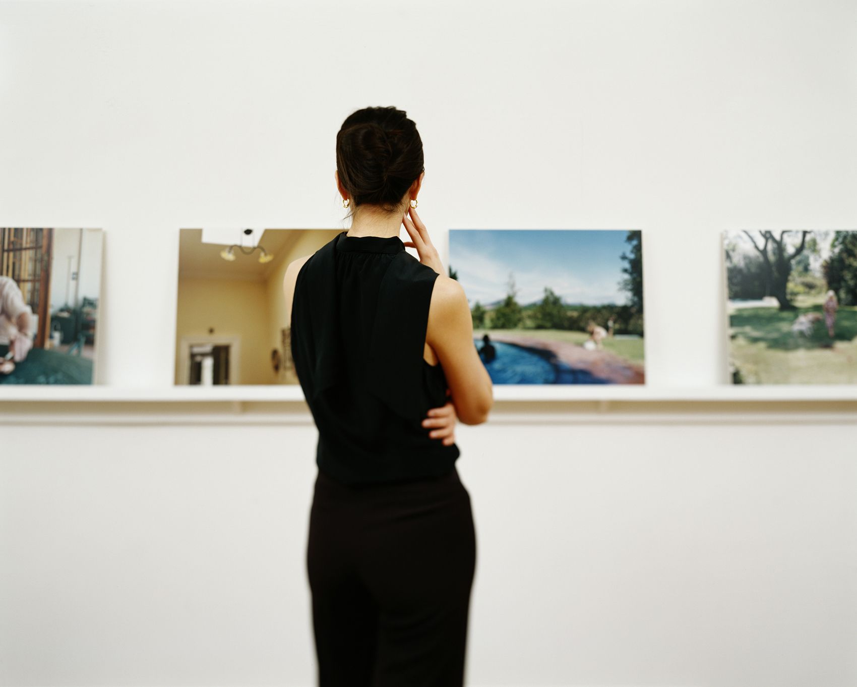 Nainen tuijottaa valokuvia taidegalleriassa