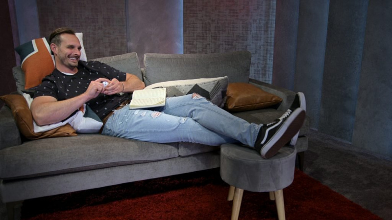  يستلقي برينون ليميو على أريكة ويستريح قدميه على كرسي.
