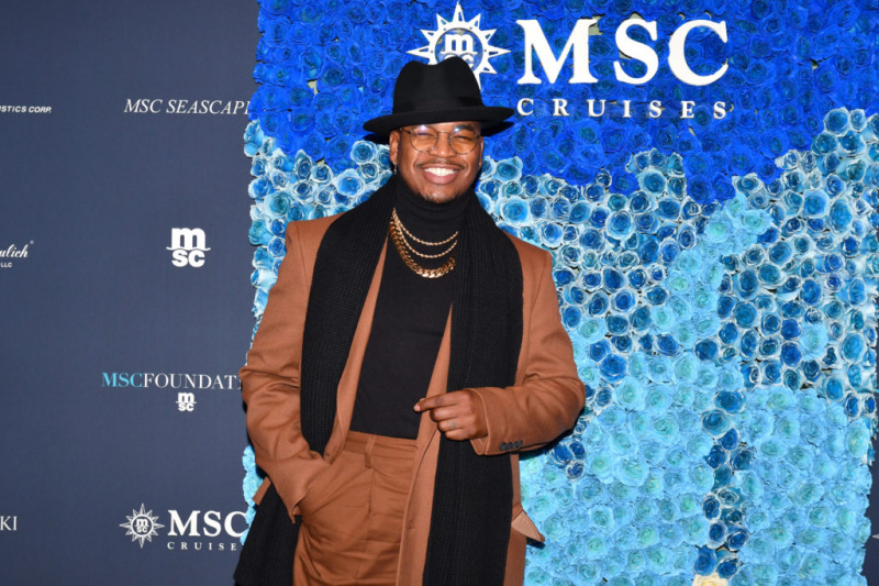   Ο Ne Yo χαμογελά στην τελετή ονομασίας του MSC Seascape στη Νέα Υόρκη φορώντας καφέ παλτό, μαύρο καπέλο και κασκόλ