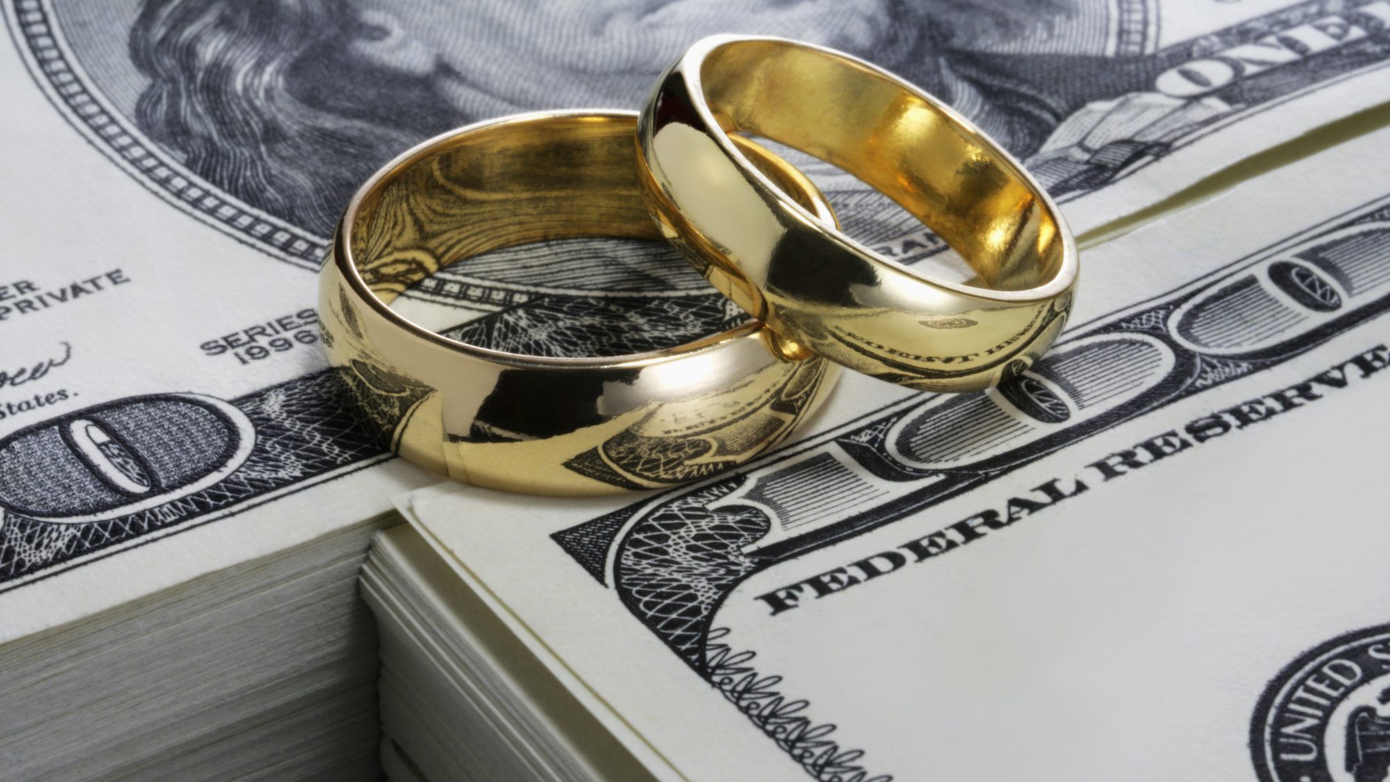すべてのカップルが結婚する前にすべき10の重要なこと：お金の上に積み上げられた金の結婚指輪