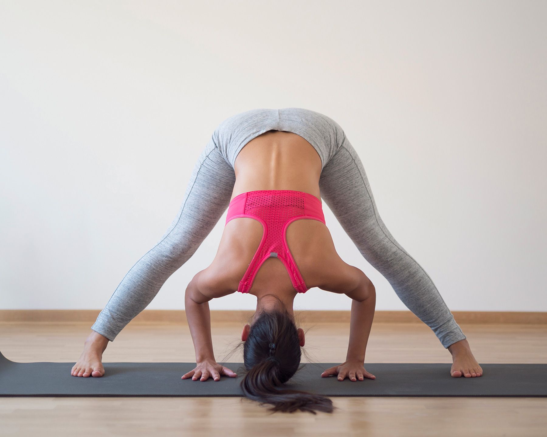 Yoga restaurativo: mujer haciendo pose de yoga de pliegue hacia adelante de gran angular